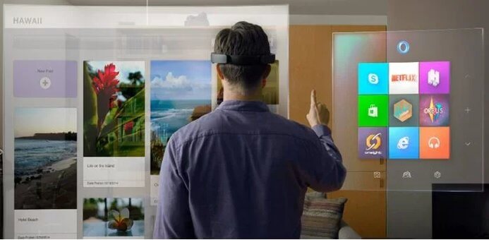 Imagem mostrando um homem virado de costas com um óculo VR e a sua frente algumas telas com aplicativos. A ideia é mostrar o que o usuário enxerga através o óculos VR