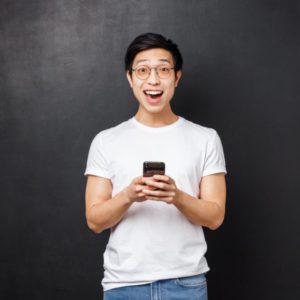 Technology, gadgets and people concept. Super happy smiling positive asian guy in glasses and t